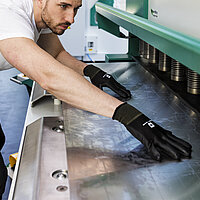 Bediener führt Sicherheitsprüfung an einer Blechbearbeitungsmaschine durch – Fokus auf Schutzvorrichtung und ordnungsgemäßer Maschinenbedienung