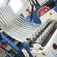 Wellblech wird mit einer Rundwalzmaschine von Hezinger präzise zu einem Zylinder geformt.